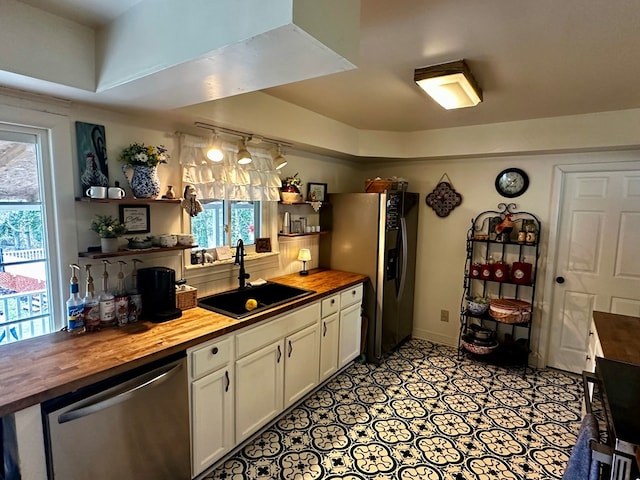 kitchen with open shelves, a sink, plenty of natural light, wood counters, and stainless steel appliances