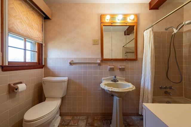 full bathroom with shower / bath combo with shower curtain, toilet, tile walls, and wainscoting