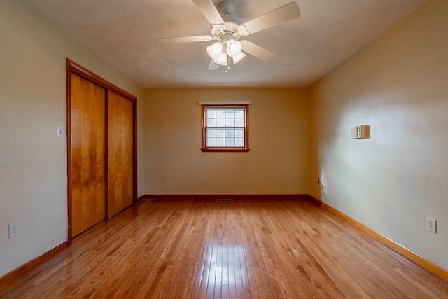 unfurnished bedroom with a closet, a ceiling fan, light wood-type flooring, and baseboards