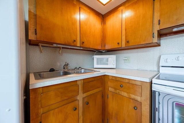 kitchen featuring light countertops, decorative backsplash, brown cabinets, white appliances, and a sink