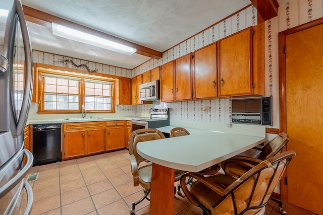 kitchen featuring wallpapered walls, appliances with stainless steel finishes, light tile patterned flooring, brown cabinetry, and light countertops