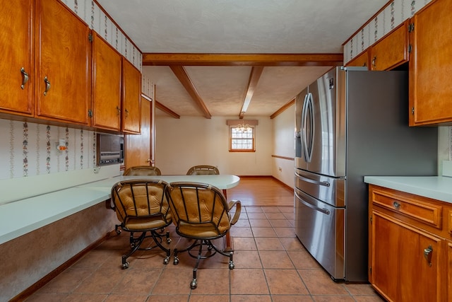 kitchen with light countertops, light tile patterned floors, brown cabinetry, and built in study area