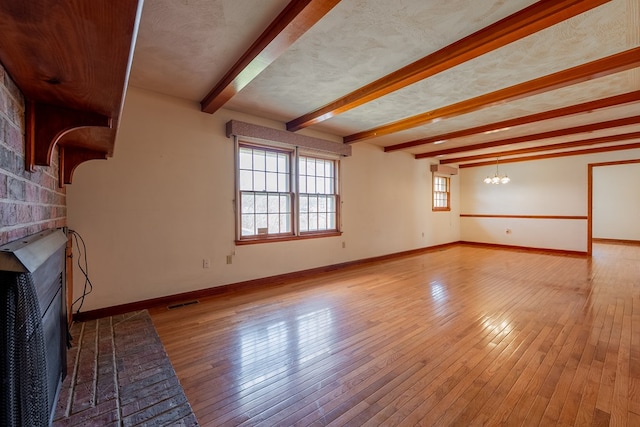 unfurnished living room with a notable chandelier, baseboards, light wood-style floors, and a brick fireplace