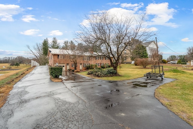 view of front of home with a front yard, aphalt driveway, a garage, and metal roof