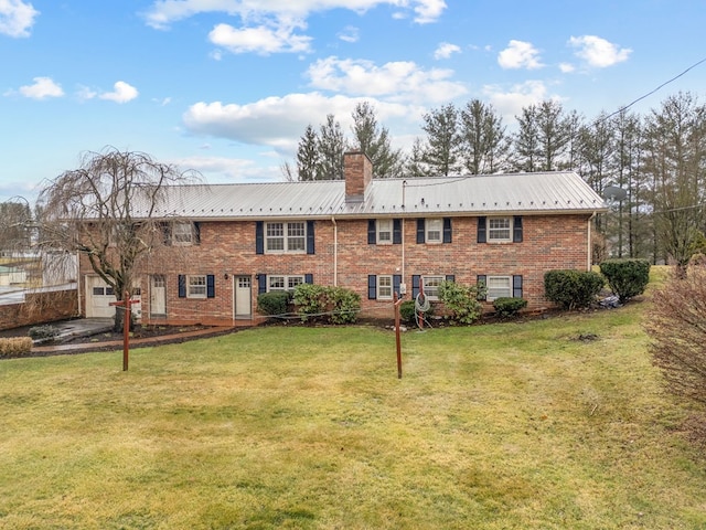 rear view of property featuring a yard, metal roof, brick siding, and a chimney