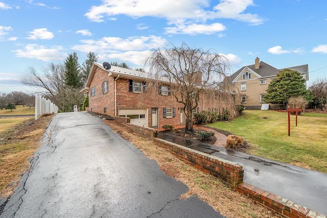 view of front of house with a front yard, brick siding, an attached garage, and driveway