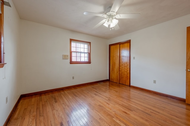 unfurnished bedroom featuring a ceiling fan, light wood-style floors, baseboards, and a closet