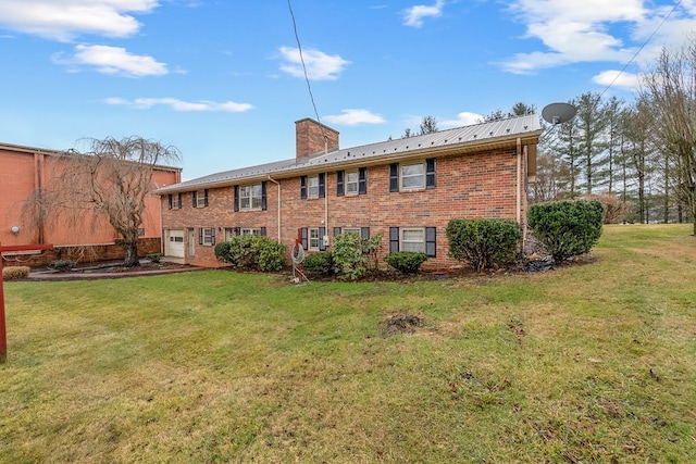 back of house with brick siding, a chimney, and a yard