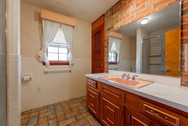 full bath featuring vanity, tile walls, a shower with shower door, and wainscoting