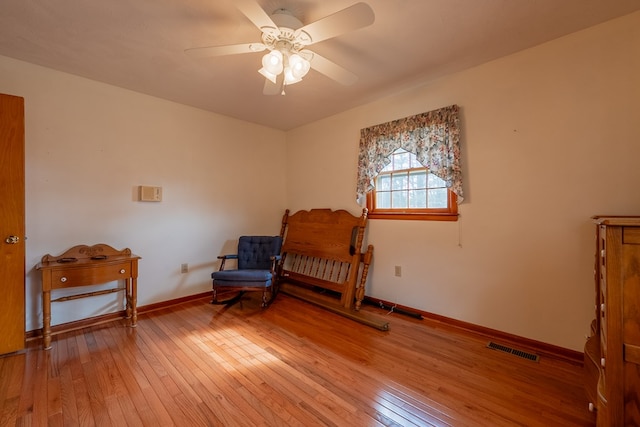 living area featuring visible vents, baseboards, light wood-style floors, and a ceiling fan