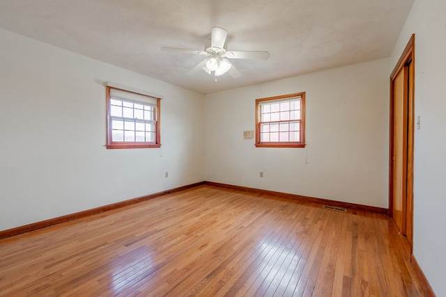 unfurnished room with a wealth of natural light, visible vents, light wood-type flooring, and baseboards