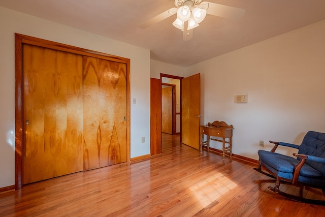 living area with baseboards, a ceiling fan, and light wood finished floors