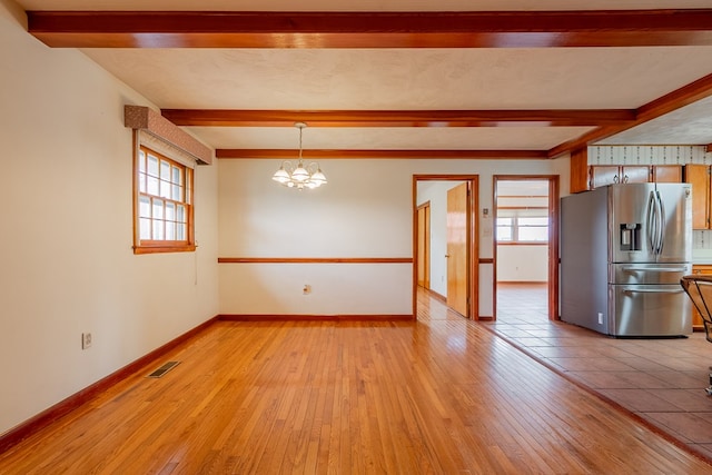 interior space featuring baseboards, visible vents, beam ceiling, a notable chandelier, and light wood-type flooring