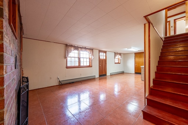 unfurnished living room featuring a baseboard heating unit, tile patterned floors, and stairs