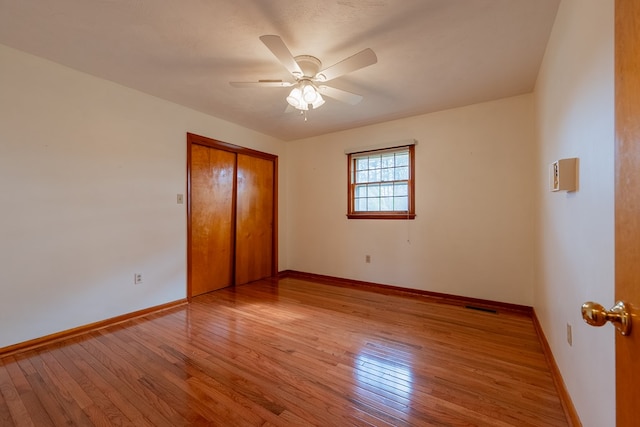 unfurnished bedroom with a closet, visible vents, baseboards, and hardwood / wood-style floors