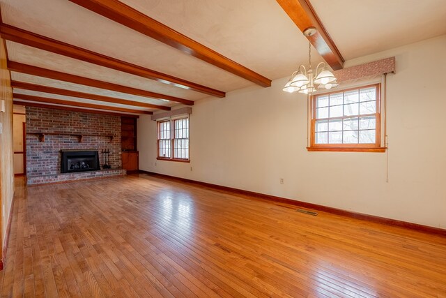 unfurnished living room with beam ceiling, a notable chandelier, baseboards, and hardwood / wood-style floors