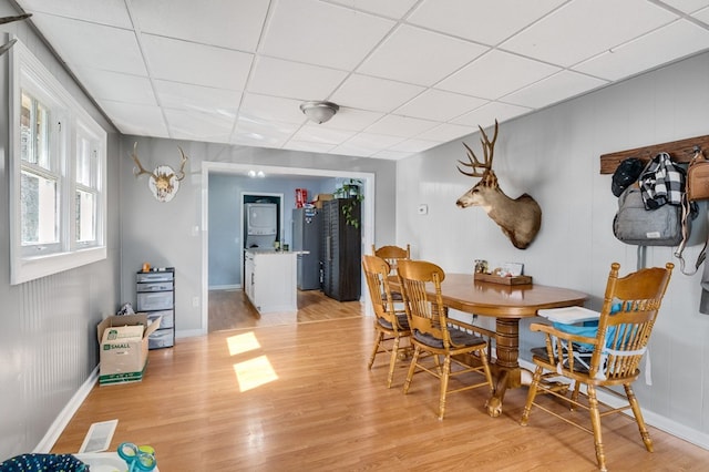 dining space with a drop ceiling, visible vents, light wood-type flooring, and baseboards