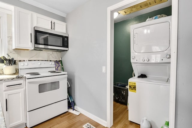 kitchen with light wood-type flooring, white electric range, stainless steel microwave, white cabinetry, and stacked washer / drying machine