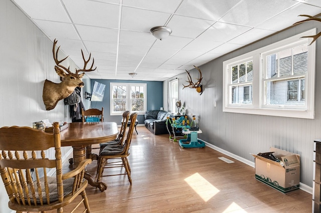 dining space featuring visible vents, a paneled ceiling, baseboards, and wood finished floors