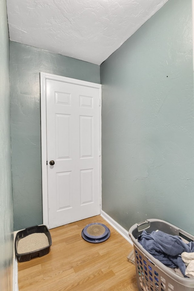 interior space featuring a textured ceiling, baseboards, and wood finished floors