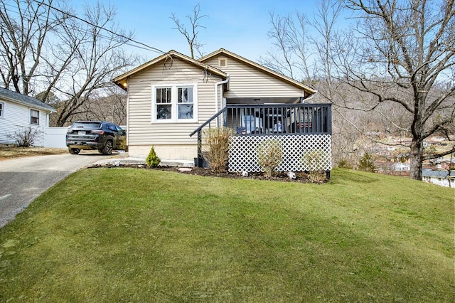 back of house with aphalt driveway and a lawn