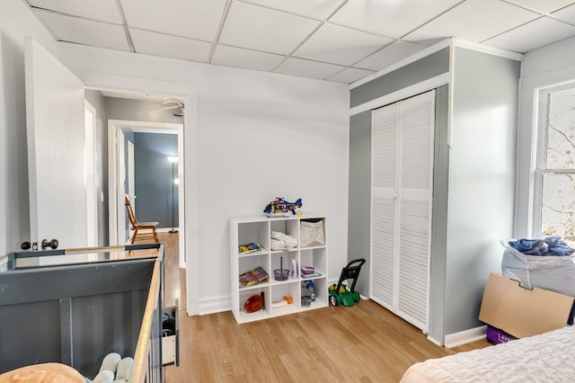 bedroom with a drop ceiling, baseboards, and wood finished floors