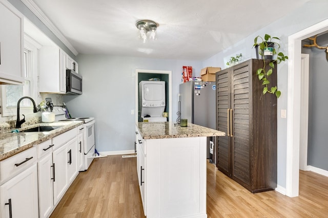 kitchen with a sink, stacked washing maching and dryer, light wood-style flooring, and stainless steel appliances