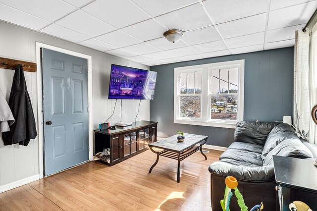 living room featuring baseboards, a paneled ceiling, and light wood-style flooring