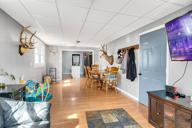 interior space featuring light wood-style floors, baseboards, and a drop ceiling