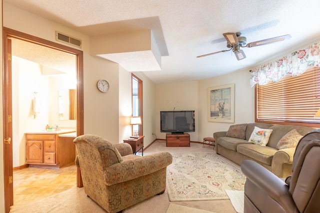 tiled living room with ceiling fan and a textured ceiling