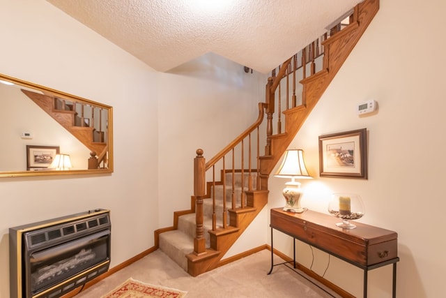 stairs featuring carpet flooring, heating unit, and a textured ceiling