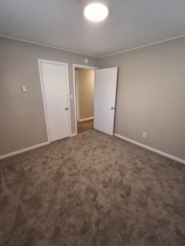 spare room with baseboards and carpet floors