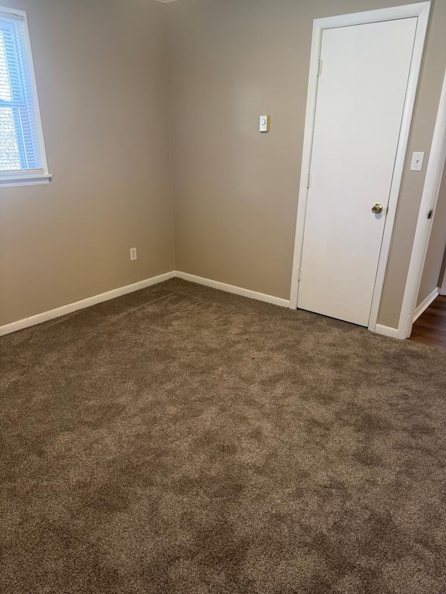 empty room with dark colored carpet and baseboards