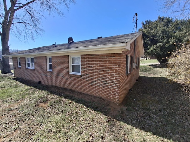 view of property exterior featuring brick siding, roof with shingles, and a chimney