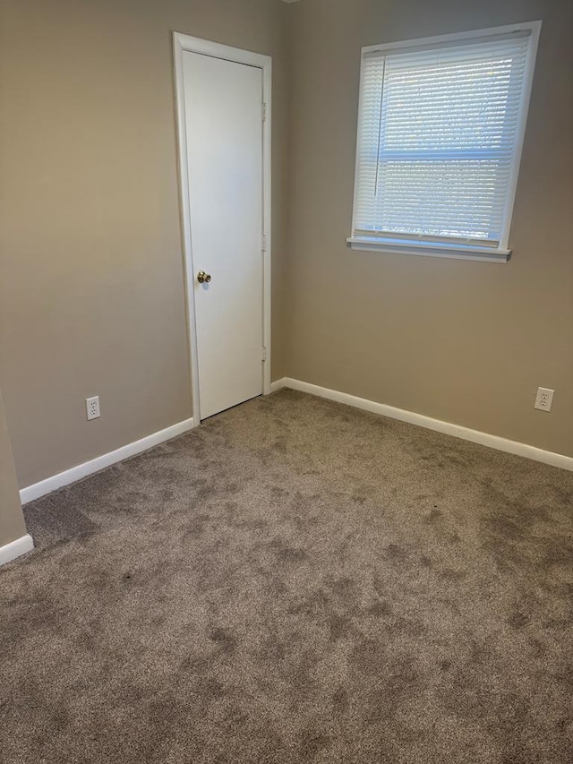 carpeted empty room with baseboards