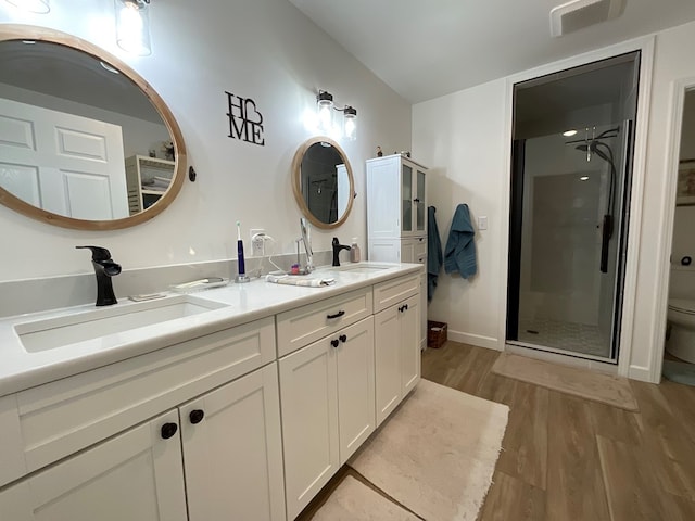 bathroom featuring a stall shower, toilet, a sink, and wood finished floors