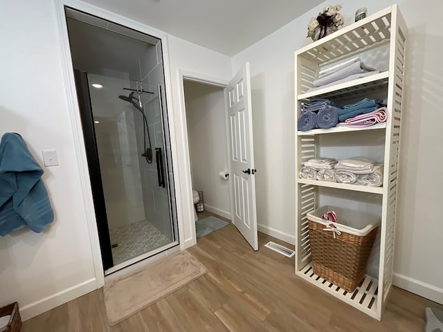 bathroom featuring baseboards, a shower stall, toilet, and wood finished floors