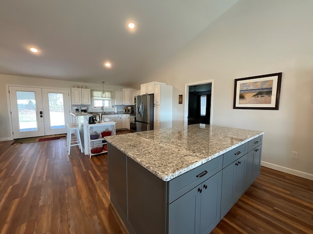 kitchen featuring a kitchen island, dark wood-style flooring, stainless steel fridge, and white cabinetry