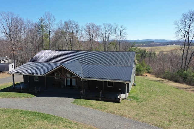 view of front of house with metal roof, driveway, and a front lawn