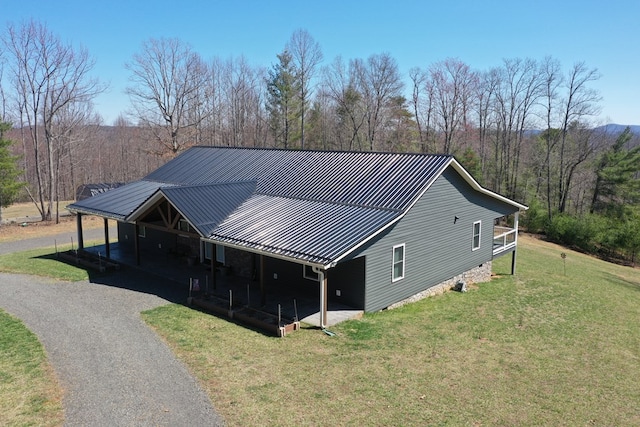exterior space with a front lawn, driveway, a standing seam roof, and metal roof