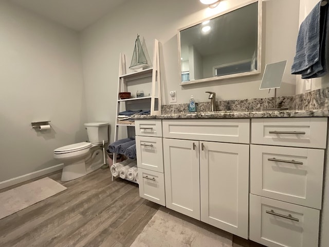 bathroom with toilet, baseboards, wood finished floors, and vanity