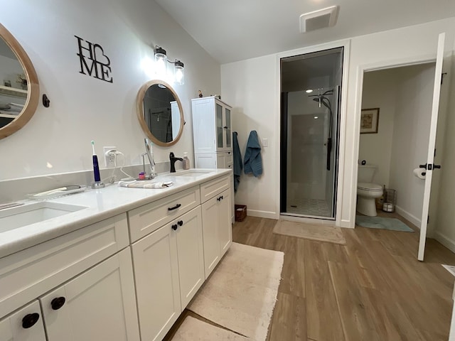 full bath with visible vents, wood finished floors, toilet, a sink, and a stall shower