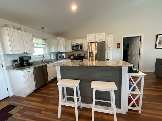 kitchen with dark wood-type flooring, white cabinetry, a breakfast bar area, and stainless steel appliances