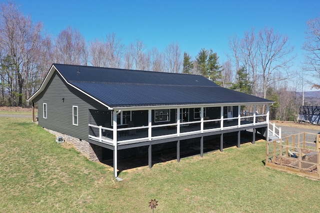 back of property with a deck, metal roof, a yard, and a vegetable garden