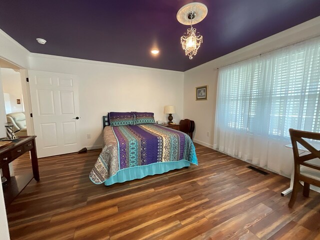 bedroom featuring baseboards, a notable chandelier, visible vents, and wood finished floors