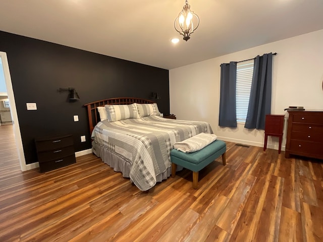 bedroom featuring a chandelier, baseboards, visible vents, and wood finished floors