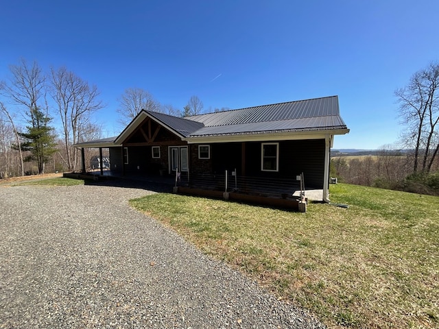 view of front of home with a porch, driveway, a front yard, and metal roof