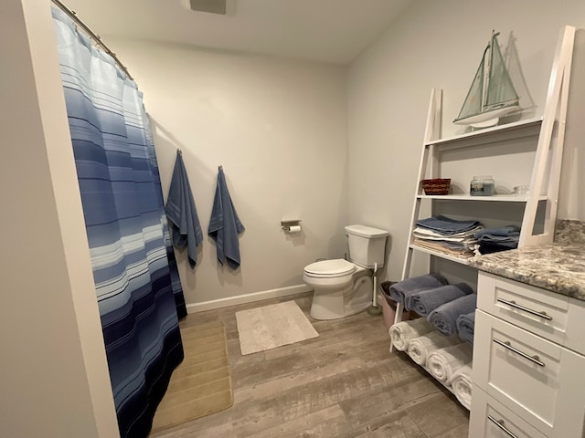 bathroom featuring wood finished floors, curtained shower, vanity, baseboards, and toilet