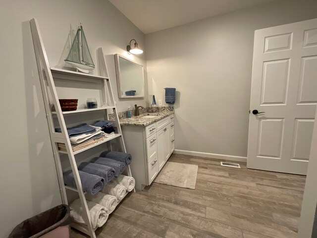 bathroom featuring baseboards, visible vents, wood finished floors, and vanity