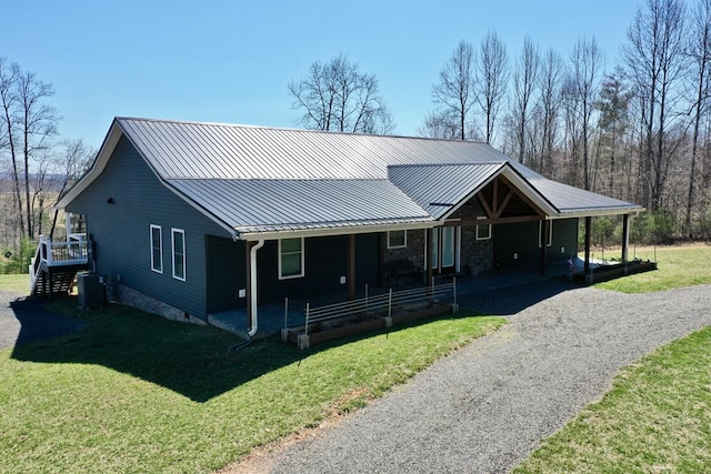 view of front of property featuring a standing seam roof, driveway, metal roof, and a front lawn